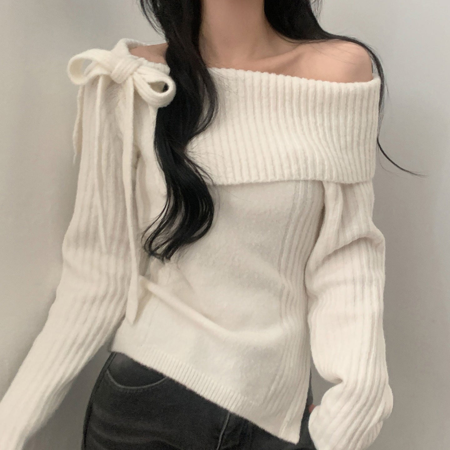 Sweter z odkrytymi ramionami, ściągaczem, kokardą i rozcięciem.